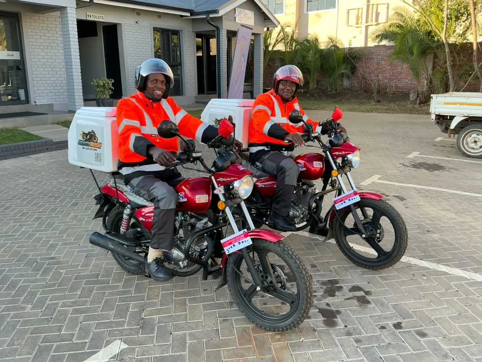 Two SmoothRush riders on branded delivery motorcycles